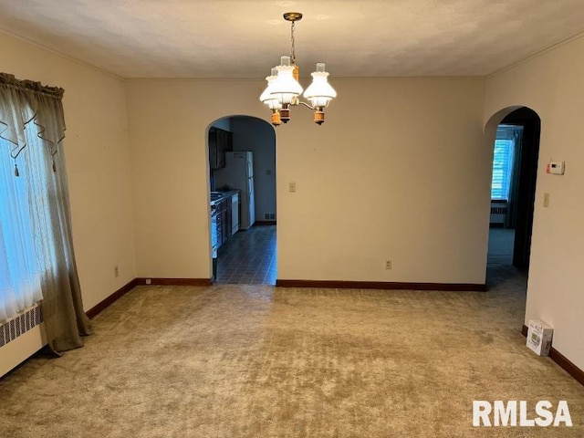 empty room featuring light colored carpet and an inviting chandelier