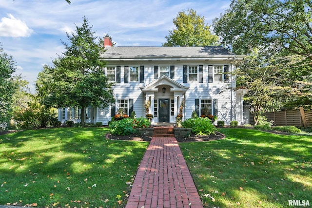 view of front of house with a front lawn, fence, and a chimney