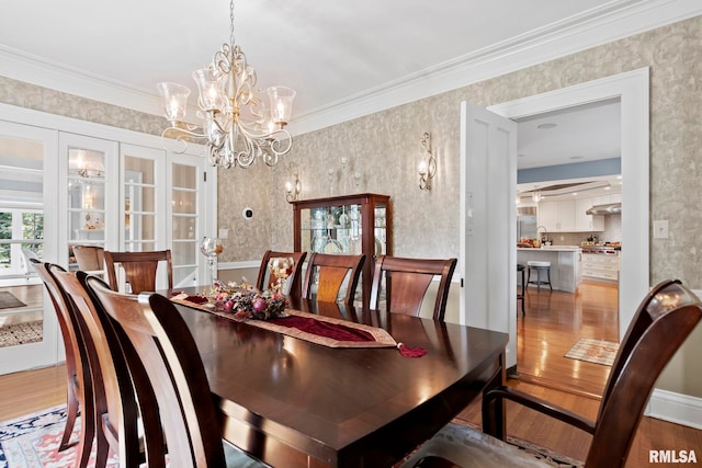 dining area featuring ornamental molding, wallpapered walls, and wood finished floors