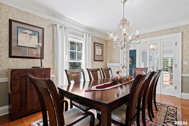 dining area with light wood-type flooring, crown molding, and an inviting chandelier