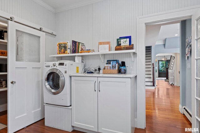 laundry room featuring cabinets, light hardwood / wood-style floors, crown molding, washer / dryer, and a barn door