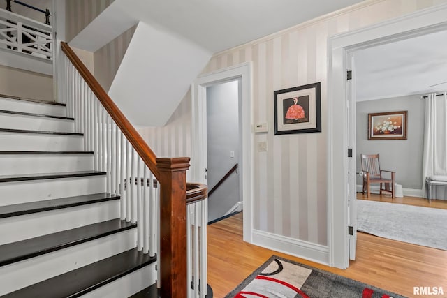 stairs featuring wallpapered walls, wood finished floors, and baseboards