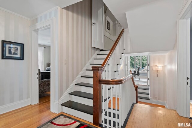 stairway with crown molding and hardwood / wood-style flooring