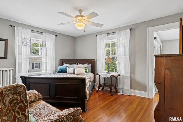 bedroom with multiple windows, wood-type flooring, and ceiling fan