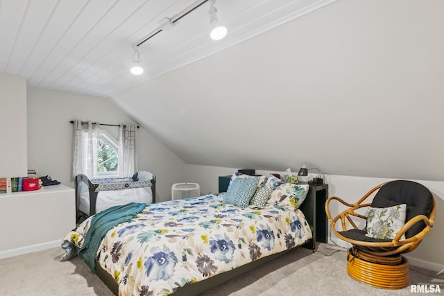 carpeted bedroom with lofted ceiling and rail lighting