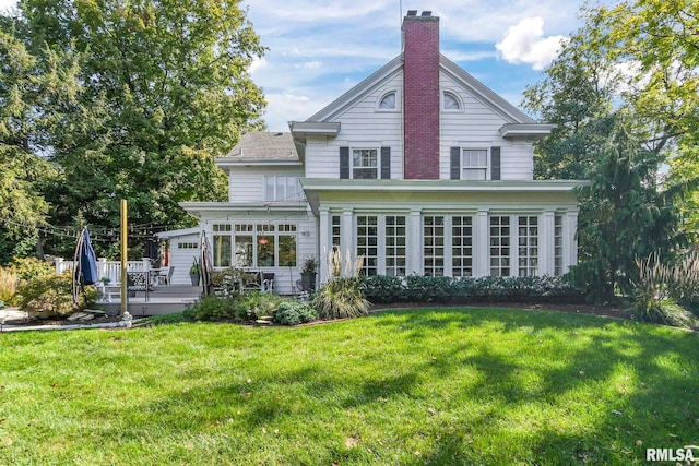 rear view of property featuring a wooden deck, a yard, a sunroom, and a chimney