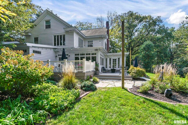 back of house featuring a wooden deck and a lawn