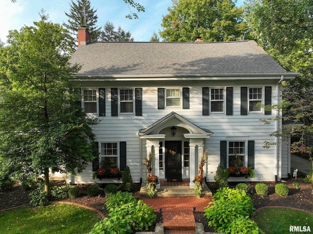 colonial-style house with a chimney and a shingled roof