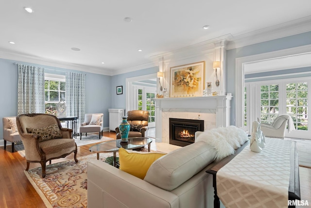 living room with light wood-type flooring, a fireplace, and ornamental molding