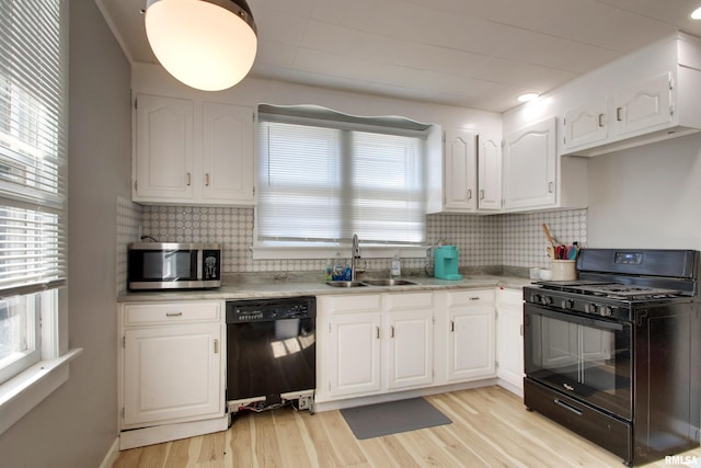 kitchen featuring black appliances, light wood finished floors, a sink, and white cabinets