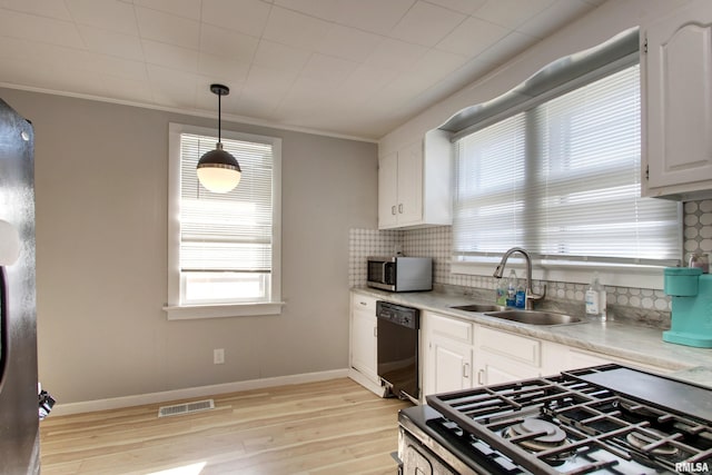 kitchen with white cabinets, decorative light fixtures, stainless steel appliances, light hardwood / wood-style floors, and sink