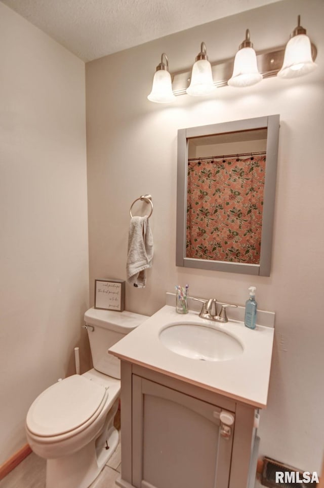 bathroom with vanity, toilet, and a textured ceiling