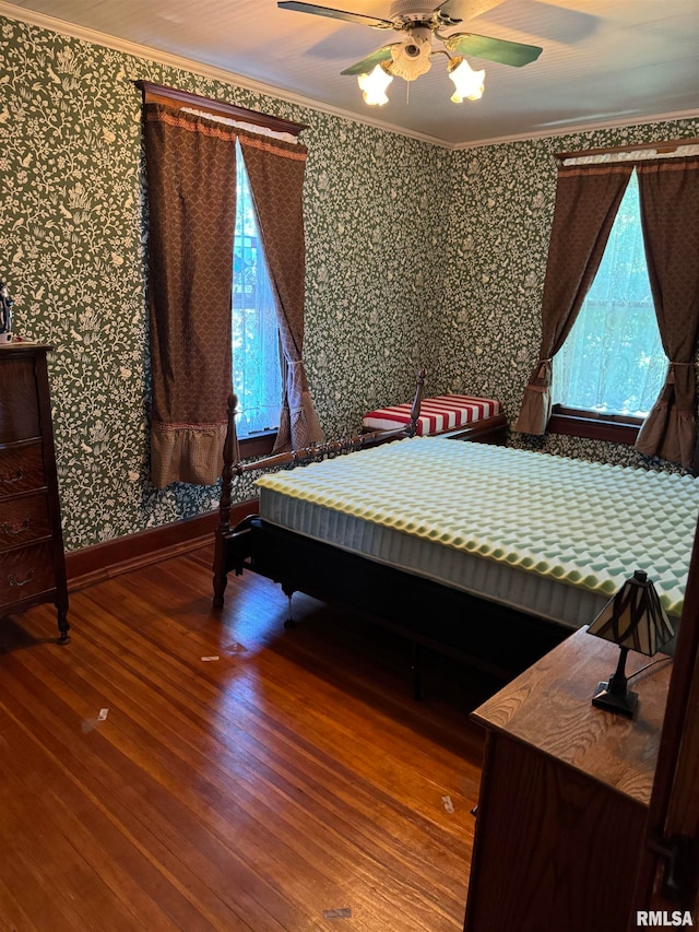 unfurnished bedroom featuring multiple windows, ceiling fan, hardwood / wood-style floors, and crown molding