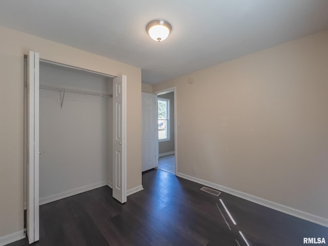 unfurnished bedroom featuring a closet and dark hardwood / wood-style flooring