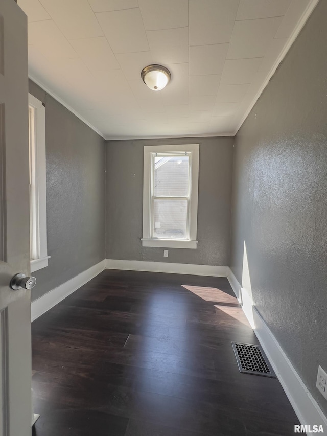 empty room with ornamental molding and dark hardwood / wood-style floors