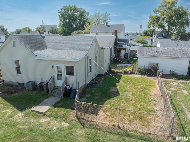 rear view of property featuring a yard and central air condition unit