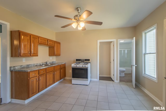 kitchen with ceiling fan, white gas range, sink, and light tile patterned flooring