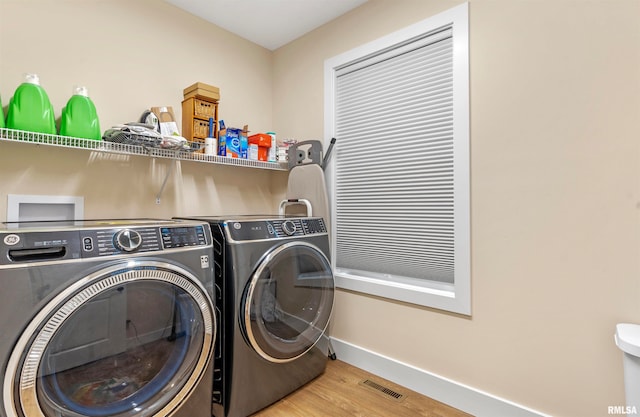 clothes washing area with independent washer and dryer and light hardwood / wood-style floors