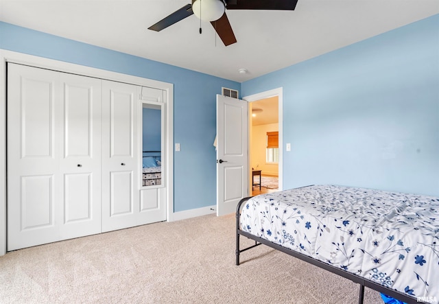 bedroom featuring light colored carpet, ceiling fan, and a closet