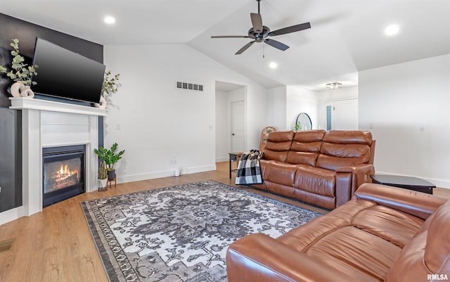 living room featuring hardwood / wood-style floors, ceiling fan, and vaulted ceiling