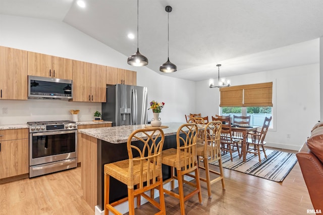 kitchen with hanging light fixtures, light wood-type flooring, appliances with stainless steel finishes, a chandelier, and lofted ceiling