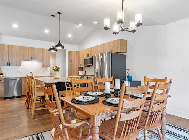 dining area featuring lofted ceiling, light wood-type flooring, and an inviting chandelier