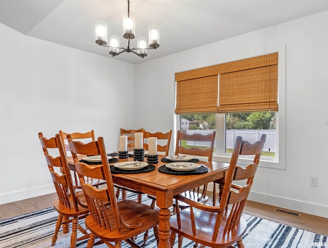 dining room with light hardwood / wood-style flooring and a notable chandelier