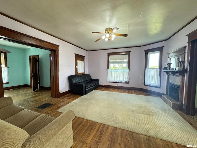 living room with ornamental molding, dark wood-type flooring, and ceiling fan