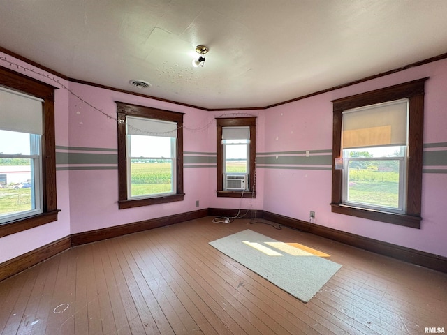 unfurnished room with hardwood / wood-style flooring, a wealth of natural light, and ornamental molding