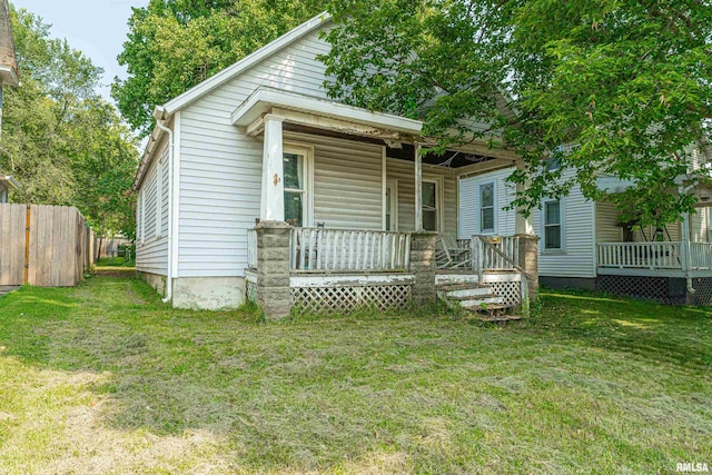 back of property with a yard and covered porch