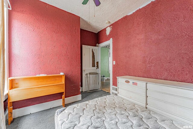 unfurnished bedroom with a textured ceiling, carpet flooring, and ceiling fan