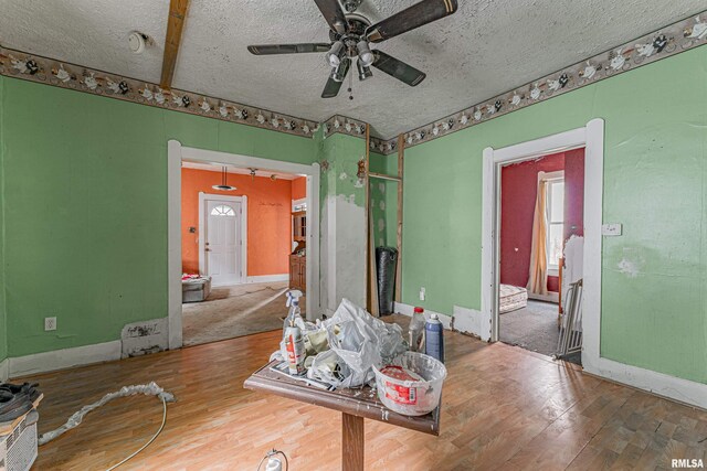 interior space with a textured ceiling, ceiling fan, and wood-type flooring