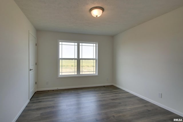 spare room with a textured ceiling and dark hardwood / wood-style floors