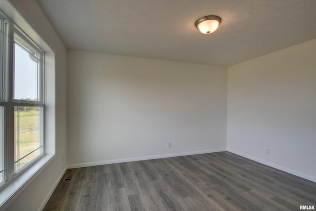 unfurnished room with a textured ceiling and dark hardwood / wood-style floors