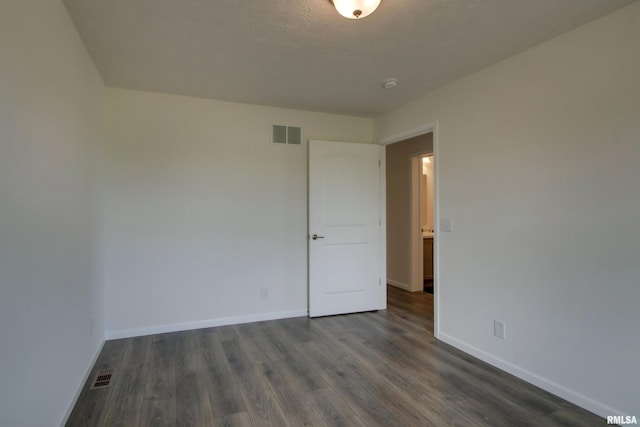 spare room featuring a textured ceiling and dark hardwood / wood-style flooring