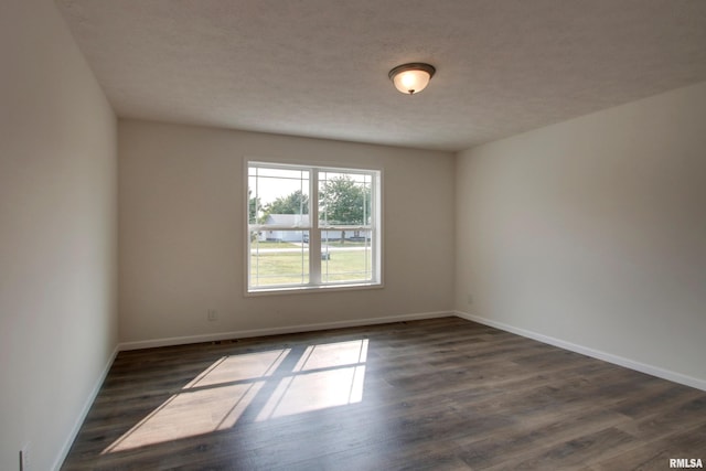 empty room with dark hardwood / wood-style flooring and a textured ceiling