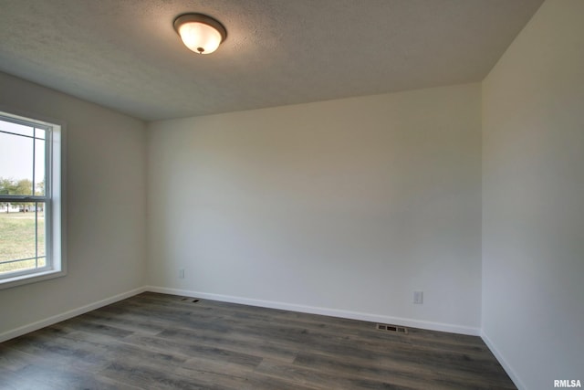 unfurnished room featuring dark wood-type flooring and a textured ceiling