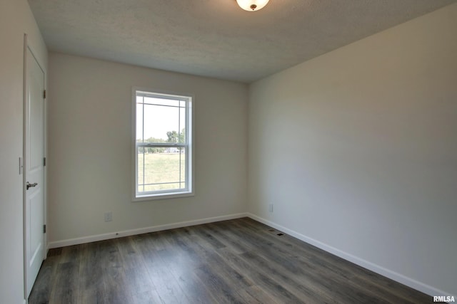 empty room featuring dark hardwood / wood-style floors and a textured ceiling