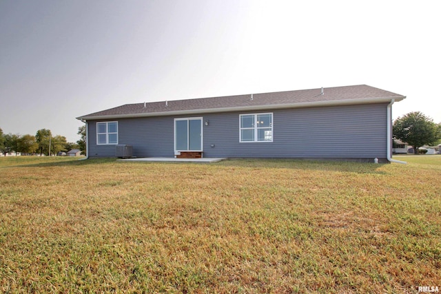 rear view of house with central AC and a yard