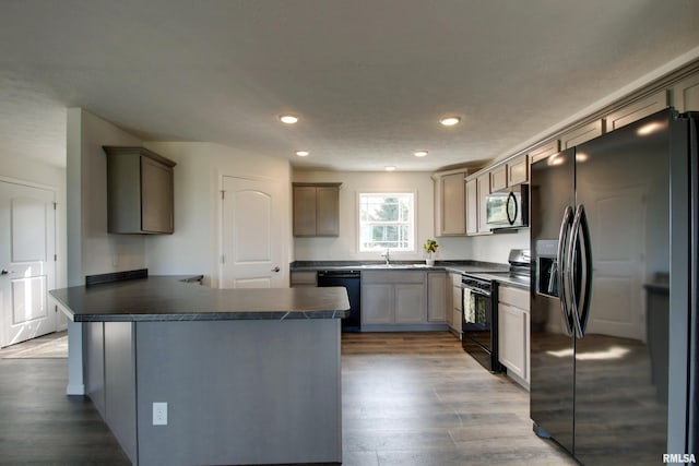 kitchen with black appliances, a textured ceiling, sink, hardwood / wood-style floors, and kitchen peninsula