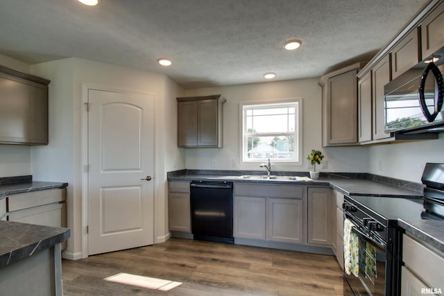 kitchen featuring a textured ceiling, sink, black appliances, and dark hardwood / wood-style flooring