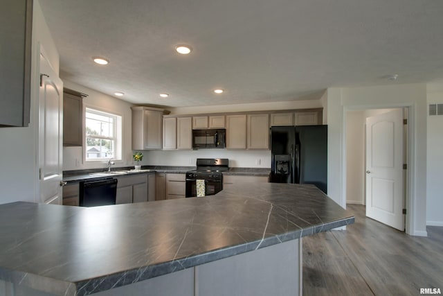 kitchen with black appliances, sink, kitchen peninsula, and wood-type flooring