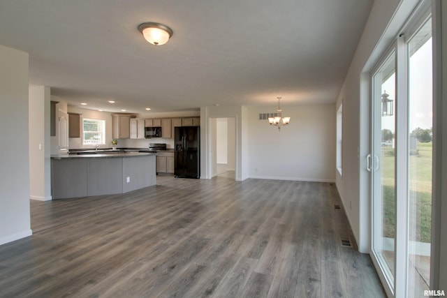 unfurnished living room featuring dark hardwood / wood-style flooring, sink, and an inviting chandelier