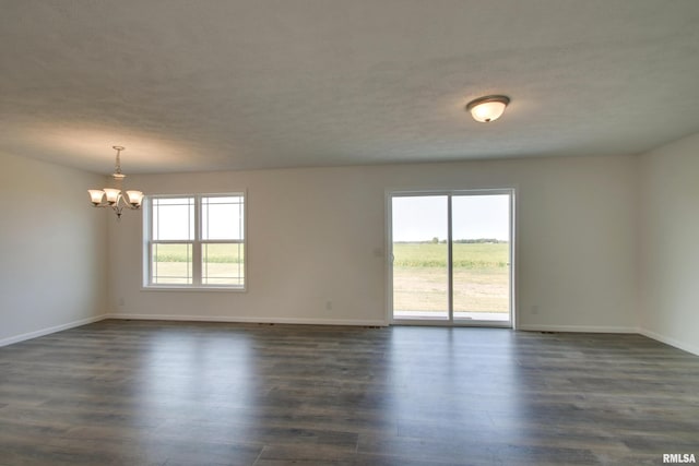 spare room featuring a chandelier, a textured ceiling, and dark hardwood / wood-style floors