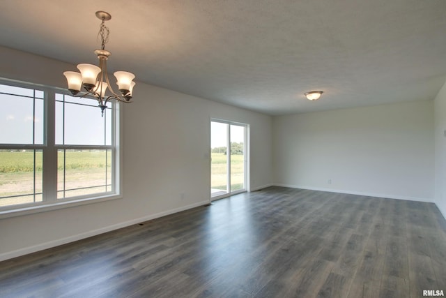 spare room with a textured ceiling, dark hardwood / wood-style flooring, and a notable chandelier