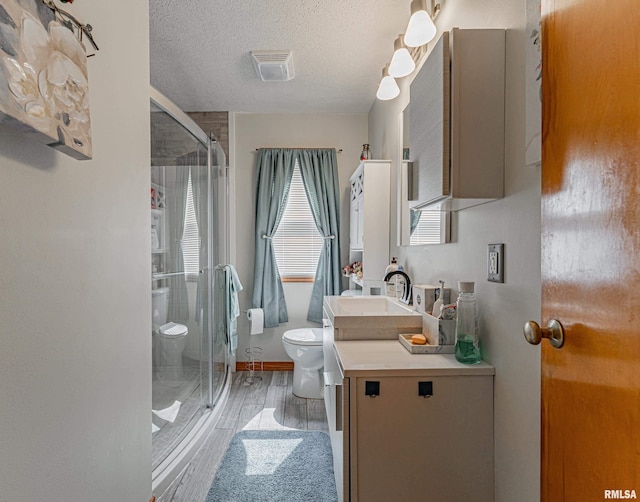 bathroom with toilet, walk in shower, vanity, a textured ceiling, and wood-type flooring