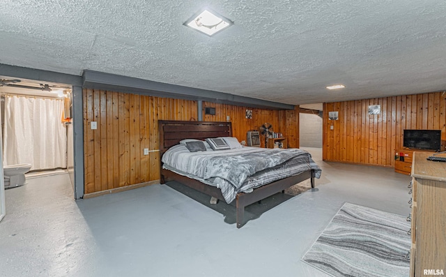 bedroom featuring wood walls, concrete flooring, and a textured ceiling