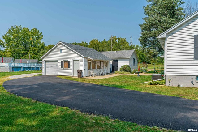 view of front of property featuring a garage, a front yard, and an outbuilding