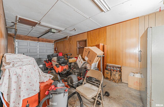 garage with white refrigerator and wooden walls