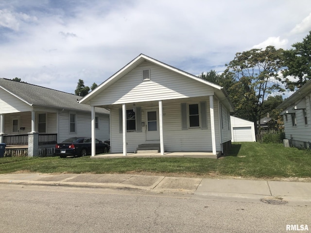 bungalow-style house featuring a garage, an outdoor structure, a front yard, and covered porch